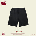 Child wearing solid colour loose cotton sports shorts in a neutral shade.