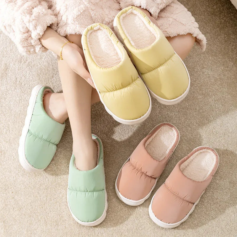 A pair of thick-soled house slippers with an artificial leather upper and plush lining, shown in a selection of colours.