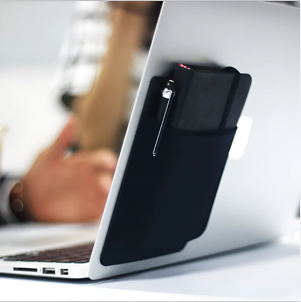 Black adhesive laptop back storage bag attached to a laptop, 15x12 cm, with pen loop and small items inside