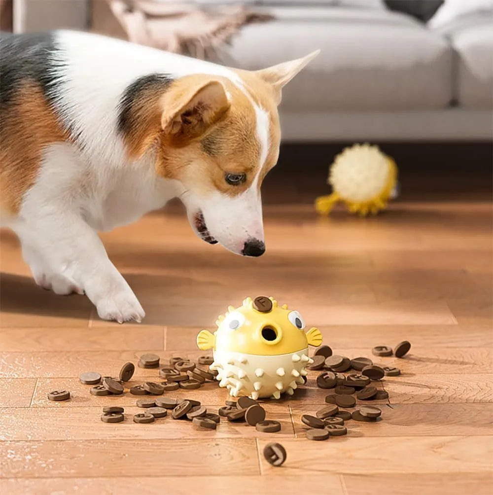 Green fish-shaped interactive dog toy with treat hole and textured surface, shown next to dog treats.
