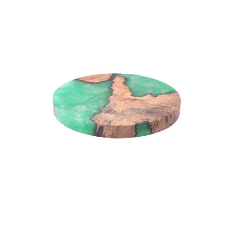 A solid black round resin coaster for a tea set, 9.8cm across and 1cm thick, on a wooden surface.