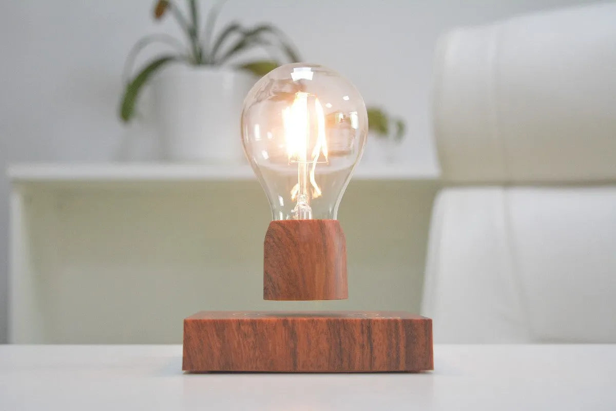 Magnetic levitation desk lamp with a floating glass bulb above an imitation wood base.