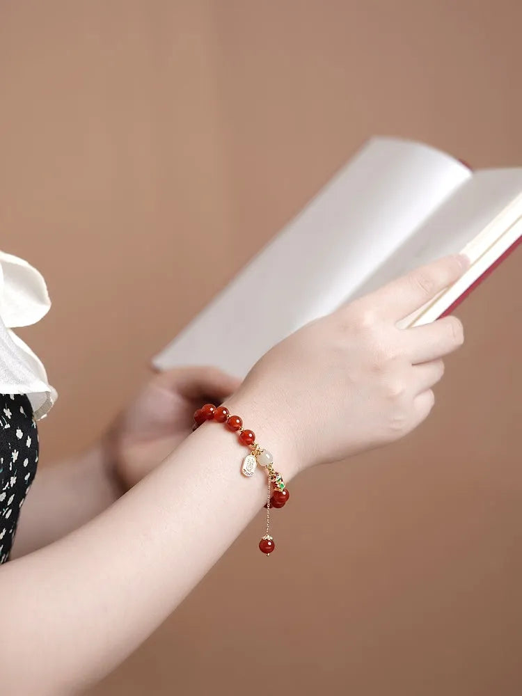 Women's bracelet with red agate and Hetian jade beads on gold-plated links in three design styles.