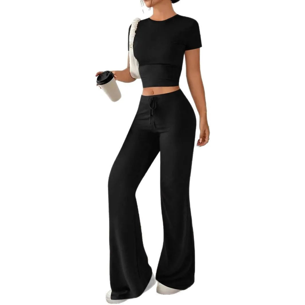 A woman's black high-waist trousers and matching short-sleeve T-shirt co-ord set laid flat.