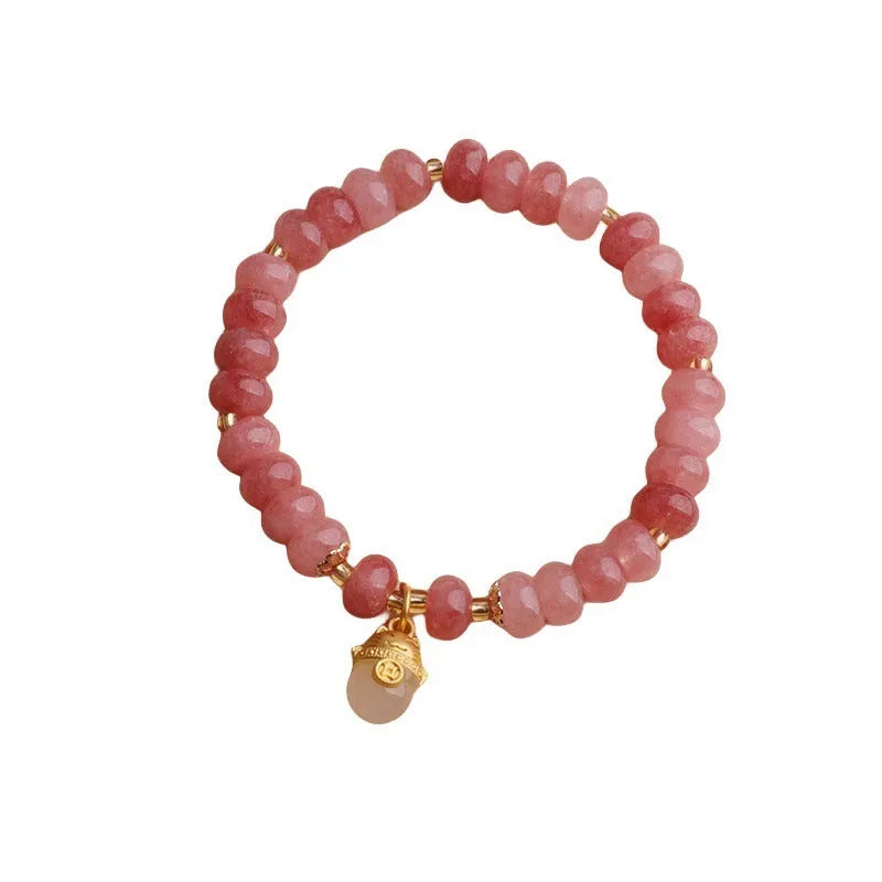 Women's strawberry quartz bracelet with lucky cat charm on grey background