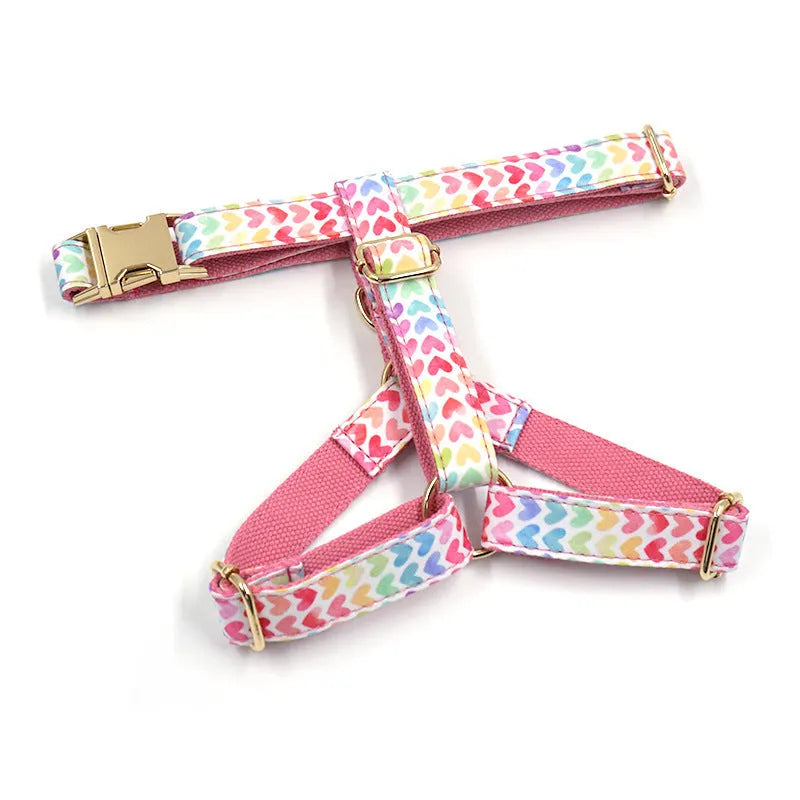 Pink dog harness with gold buckle and heart-shaped stone decoration on white background