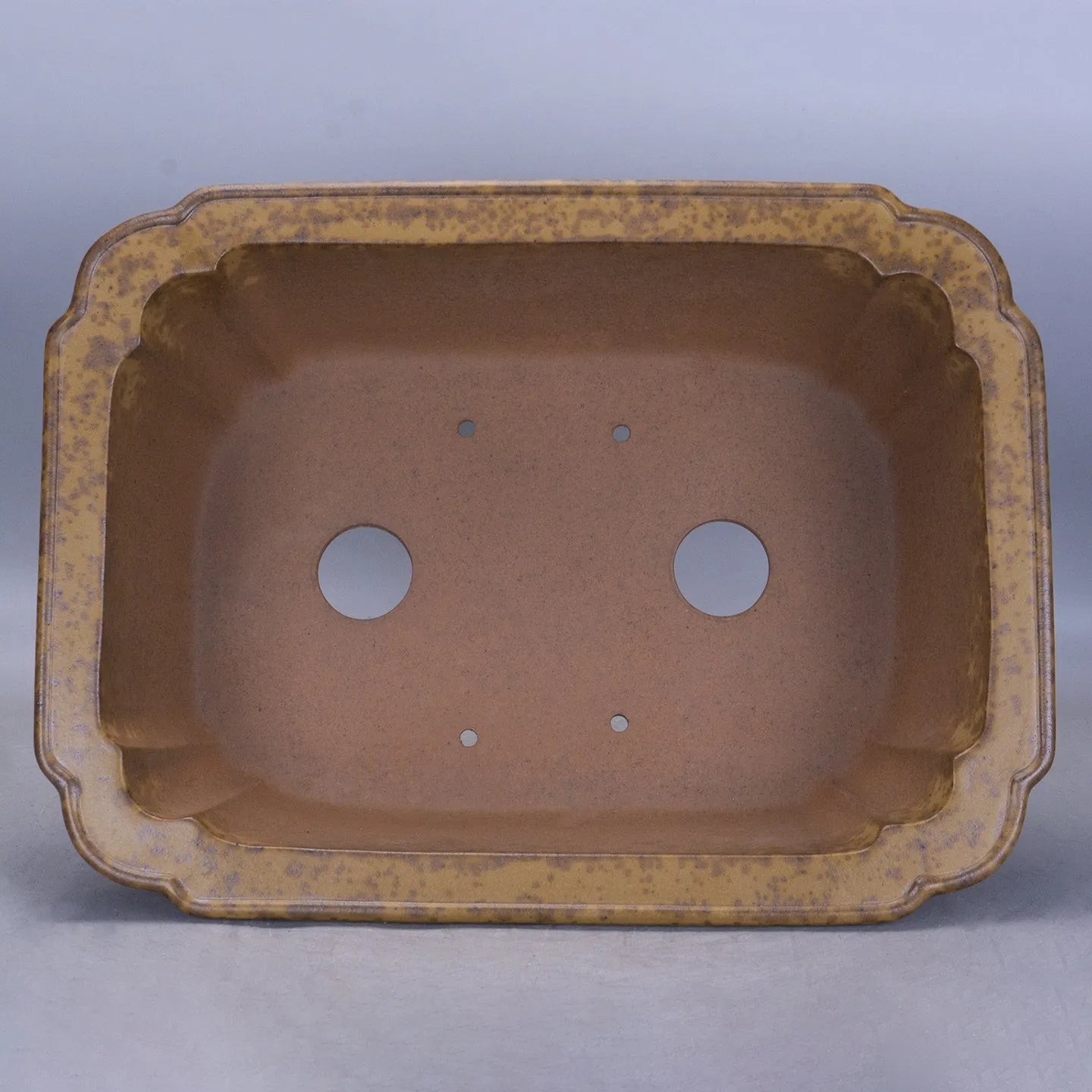 Large rectangular purple sand flowerpot with angled drainage base on a wooden patio.