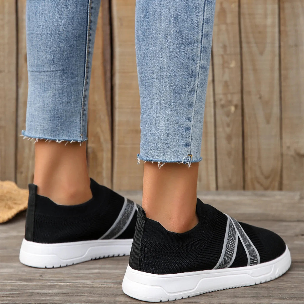 Black women's flat casual shoes with flyknit mesh upper and tassel detail on a flat rubber sole.