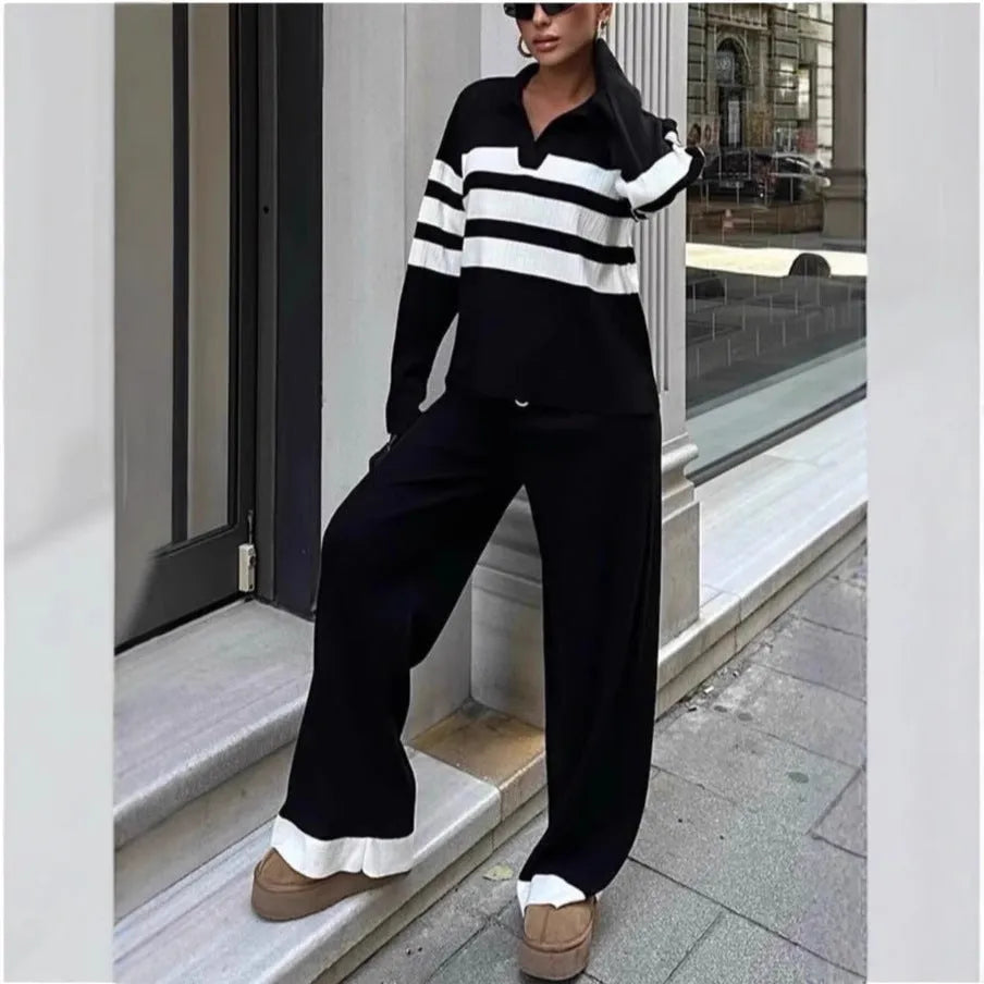 Women's black and white striped knitted two-piece set with polo collar top and straight-leg trousers laid flat.