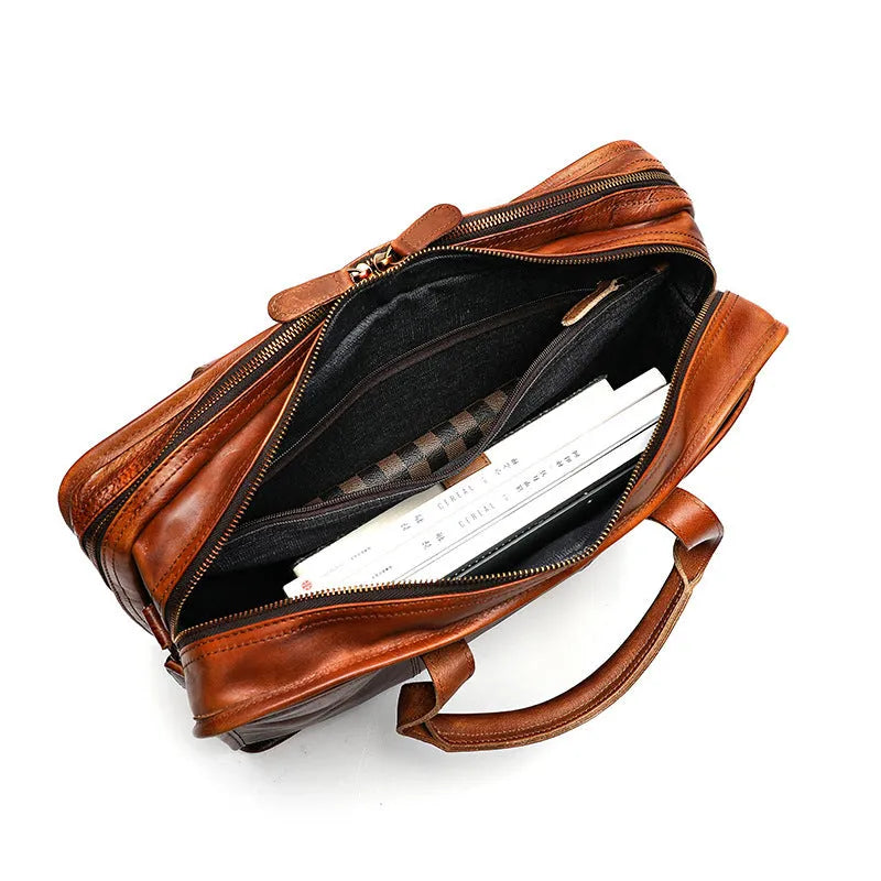 Brown vintage men's leather briefcase open to show internal laptop, document, and camera pockets.