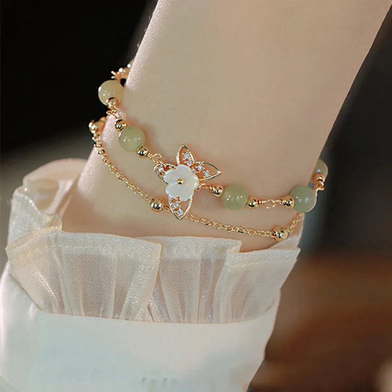 Yellow gold electroplated butterfly bracelet with shell flower design and Hetian jade accents on geometric copper jewellery