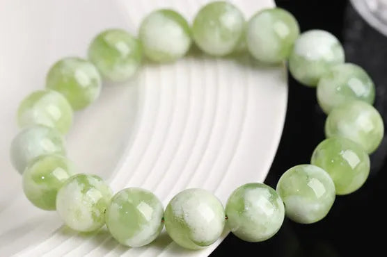 Green milk-in-water Xiuyan jade bracelet with polished geometric beads on a wrist.