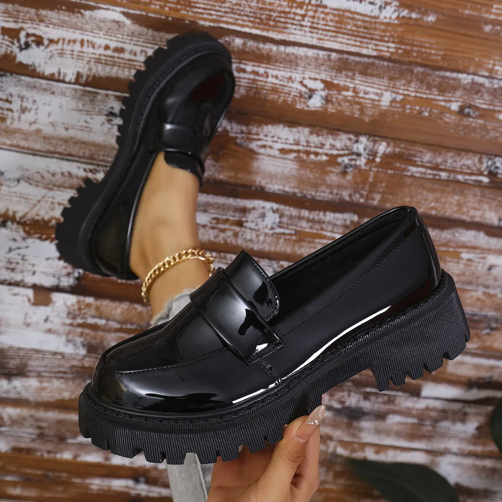 Women's black slip-on loafers with a chunky rubber sole and thick platform heel.