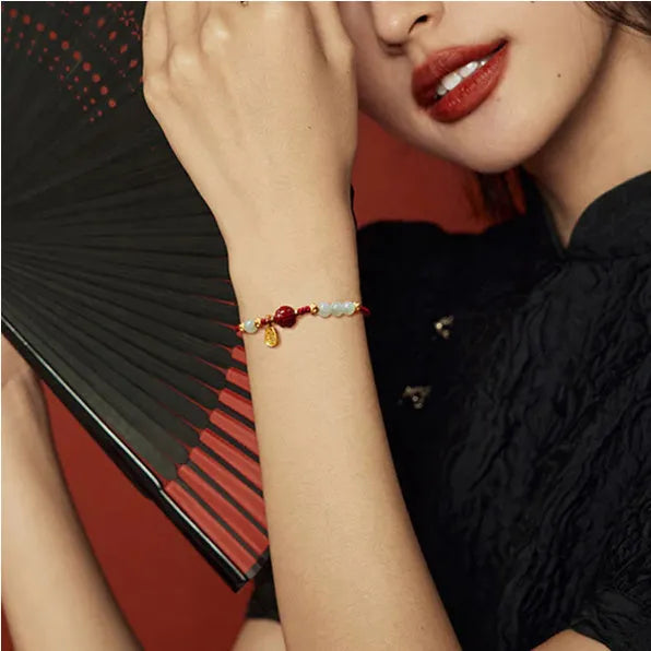Adjustable silver bracelet with red Hetian jade detail on a wrist.