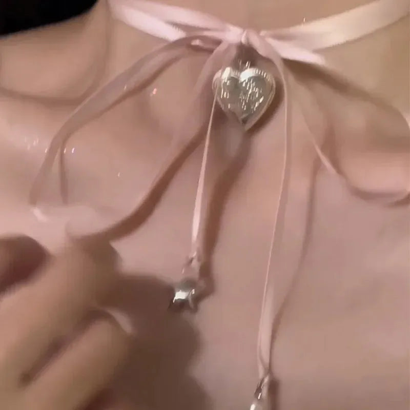 Women's ribbon love pendant necklace on a clavicle chain in an electroplated alloy, shown in one of 33 colour options.