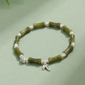 Women's green aventurine crystal bracelet with bamboo, strawberry quartz, and jade beads on wrist.
