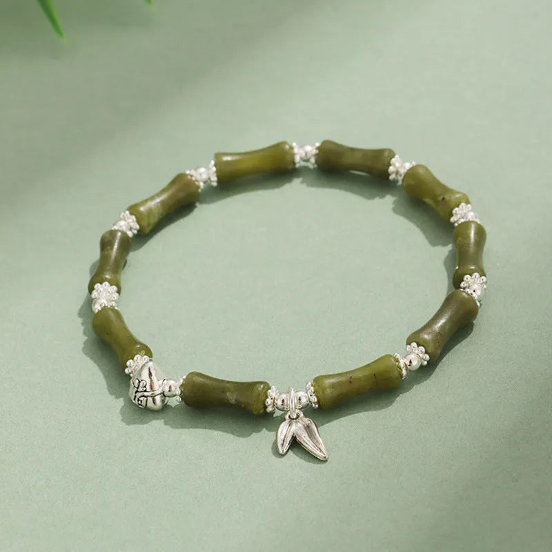 Women's green aventurine crystal bracelet with bamboo, strawberry quartz, and jade beads on wrist.