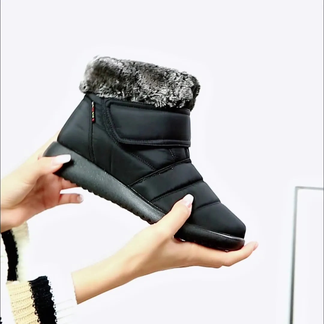 Women's winter snow boots with plush lining, suede upper, velcro strap, flat heel, and anti-skid rubber sole in black.