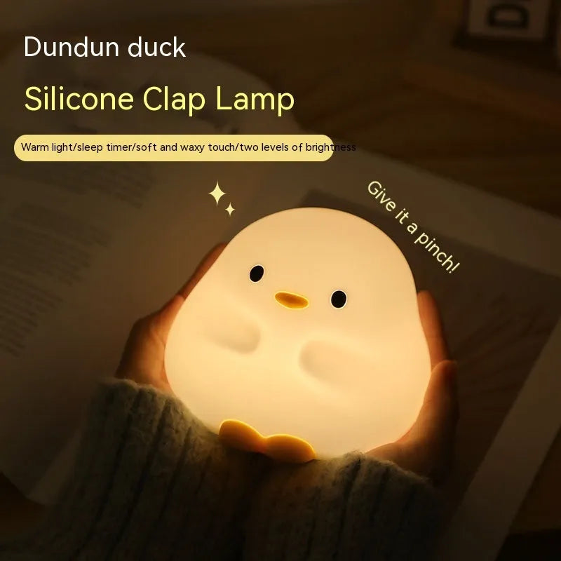 Cute duck-shaped silicone LED night lamp with touch sensor and warm glow on a bedside table