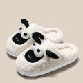 Brown suede slip-on slippers with a light-coloured PVC sole on a wooden floor.