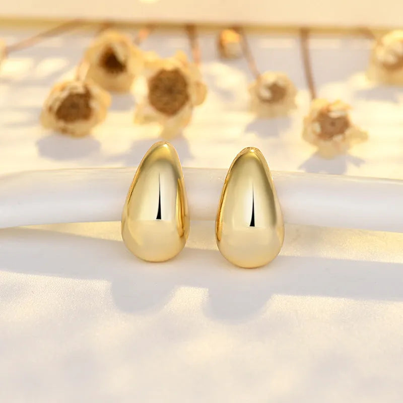 Minimalistic water drops earrings in gold plated copper, drop shape stud style on white background