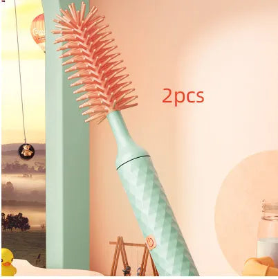 Pink and green electric rotating bottle cleaning brush with silicone bristles on a white background.