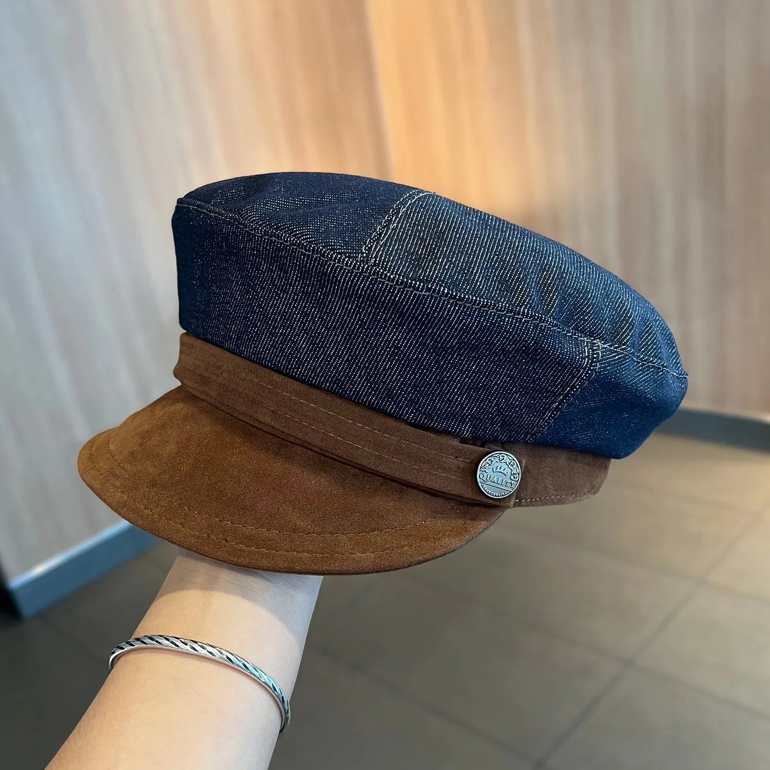 Dark blue denim octagonal newsboy flat cap with an adjustable strap, shown with a contrasting brown brim.