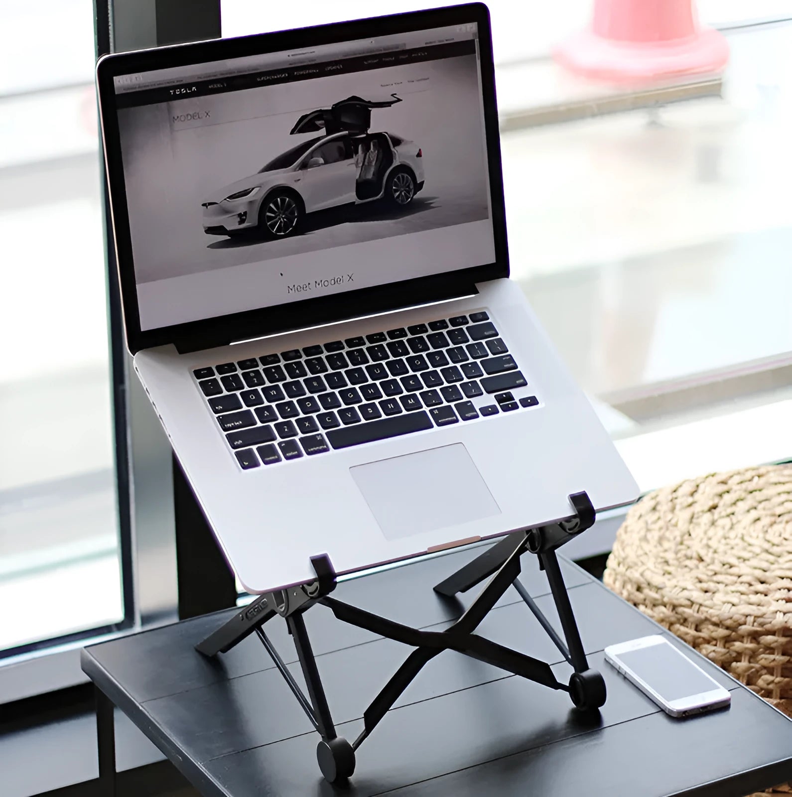 Black folding portable laptop stand made of reinforced nylon, shown in folded position.