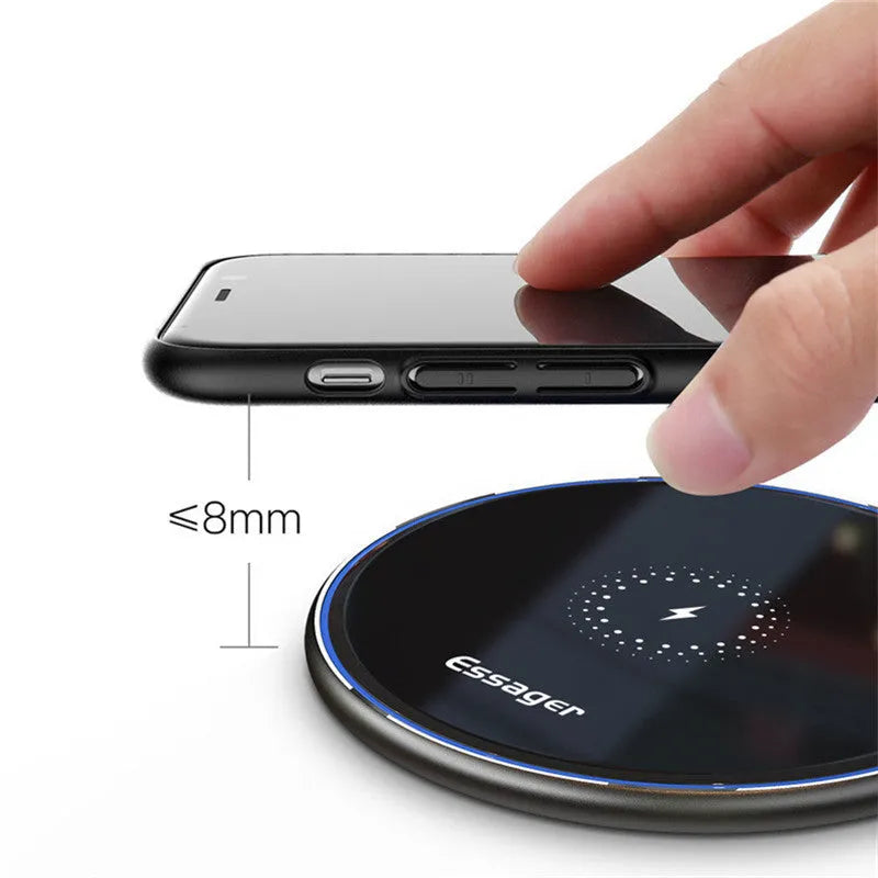 Black aluminium wireless charging pad on a desk with a mobile phone charging on top.