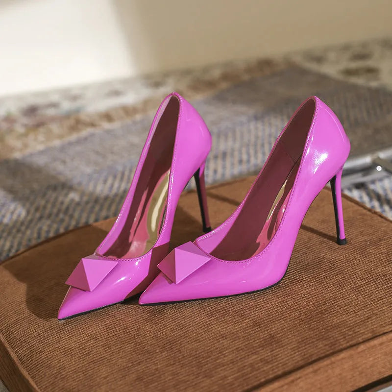 Pink patent leather women's stiletto heels with pointed toe, adjustable ankle buckle, and a slender high heel.