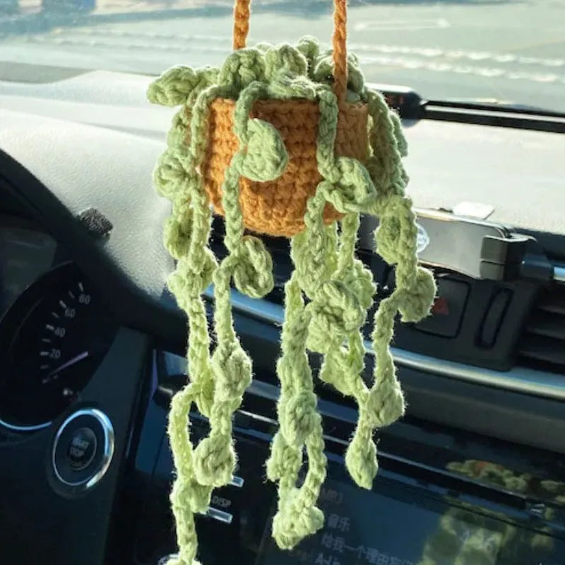Green and white crocheted wool car plant decoration with a white hanging rope.