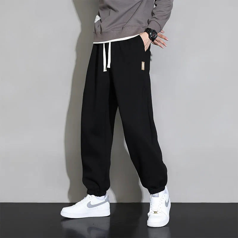 Men's loose grey cotton blend sports trousers with a drawstring waist on a hanger.