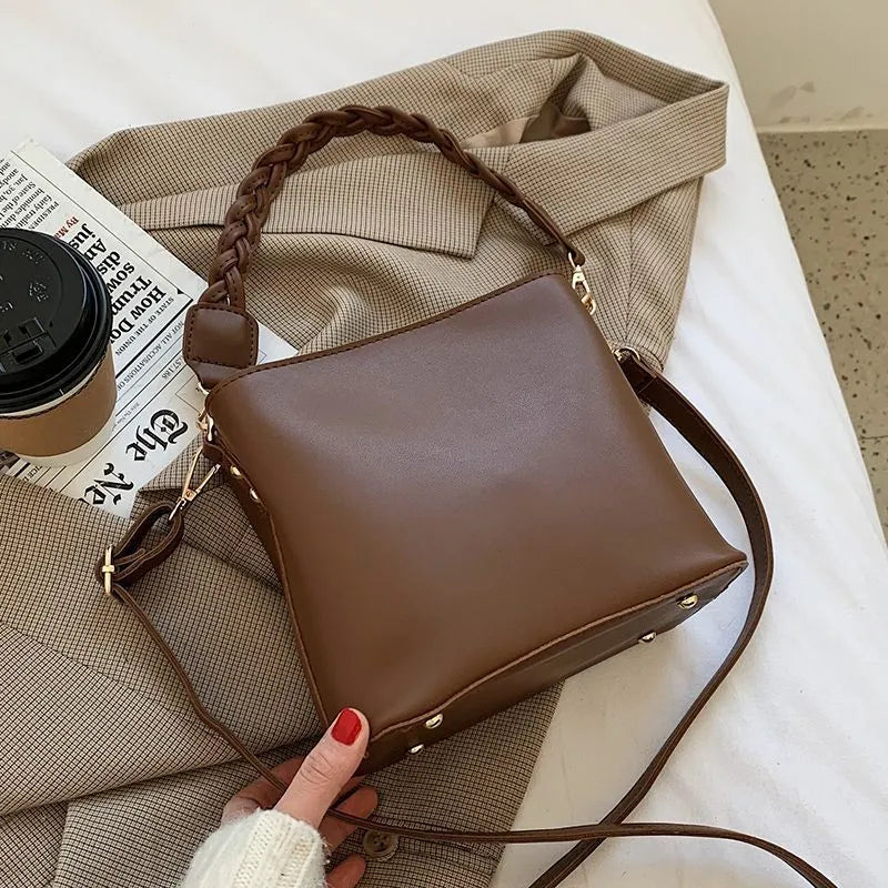 Retro style khaki woven PU leather crossbody bucket bag with an adjustable strap, shown in a casual setting.