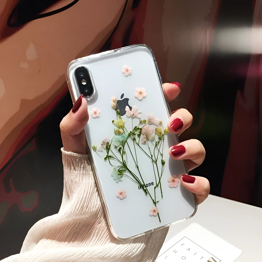 Clear TPU iPhone case showing real pink dried flowers encapsulated in epoxy resin on the back.