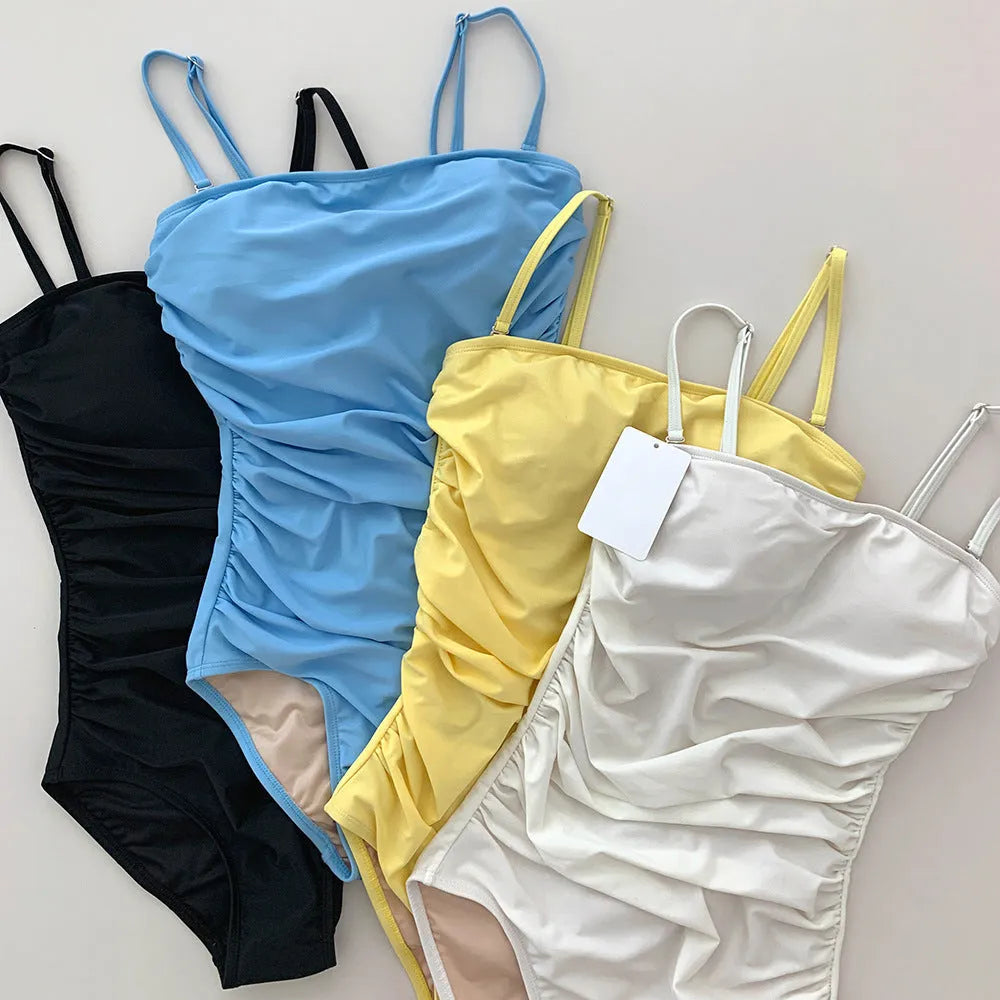 Blue one-piece sling style swimsuit with belly pleats and a slim-fit cut on a mannequin.