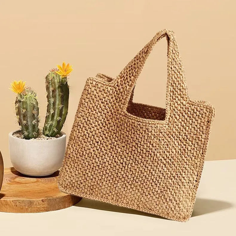 Straw woven bucket tote bag in khaki colour showing double shoulder straps and woven texture detail