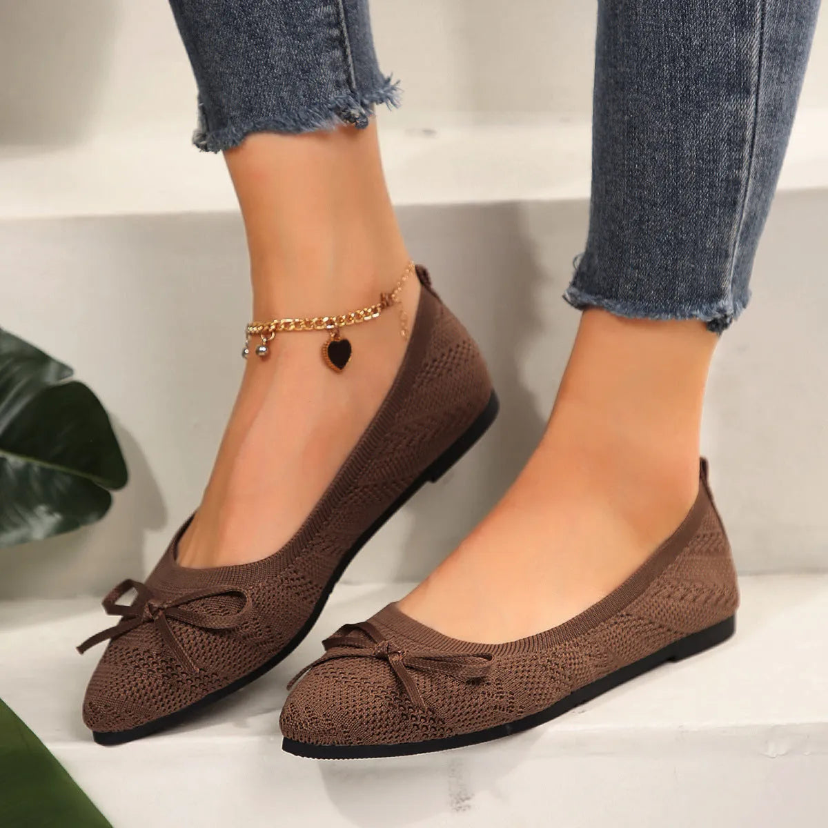Women's knitted flat shoes with a bow detail and pointed toe in various colours on a plain background.