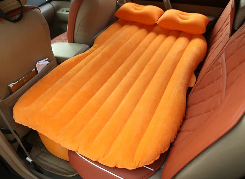 Inflatable car bed with flocked surface and two pillows, laid out in a vehicle.