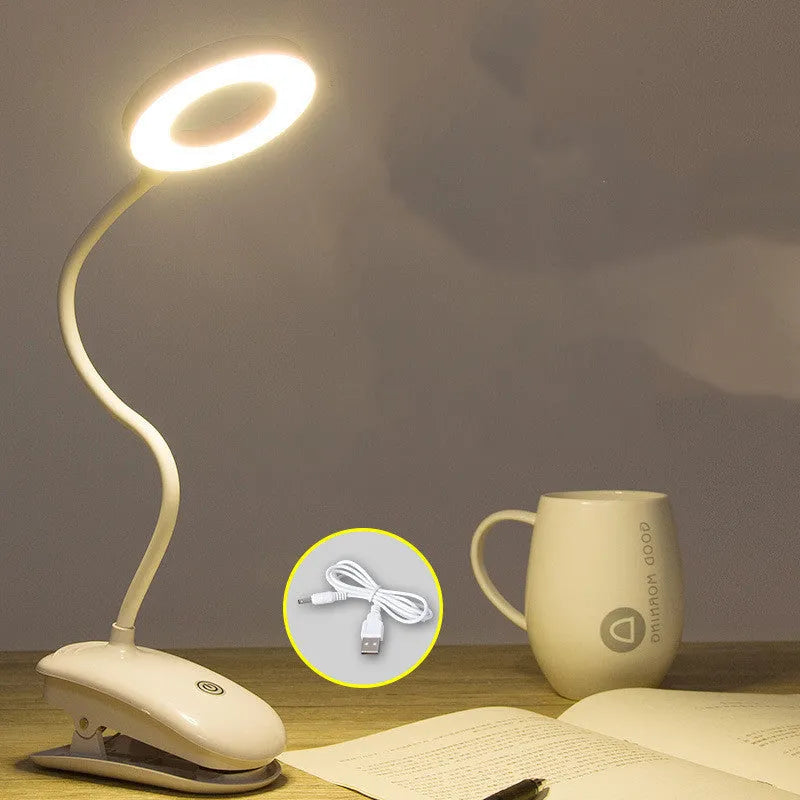 Modern clip-on rechargeable LED desk lamp with touch switch and plastic shade in use on a desk.