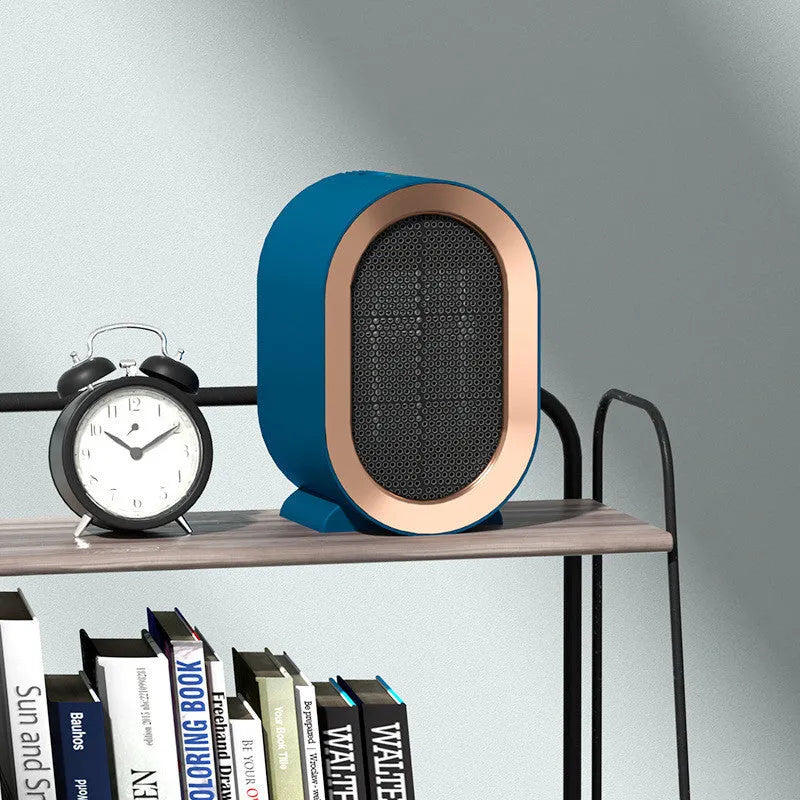 Compact desktop ceramic fan heater in black on a wooden desk.