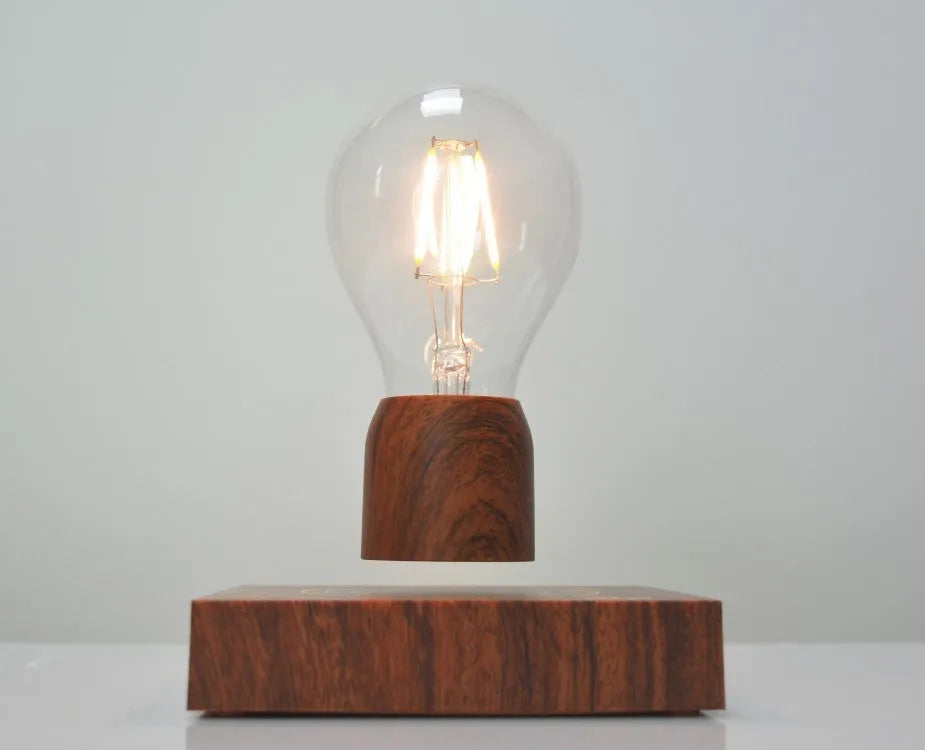 Magnetic levitation desk lamp with a floating glass bulb above an imitation wood base.