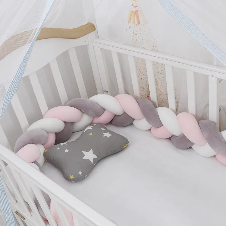Braided knot style crib bumper in spandex velvet, wrapped around white cot rails in a nursery.