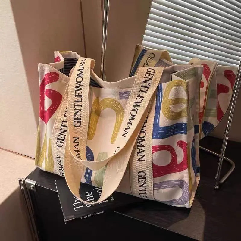 Large canvas women's tote bag with printed design, shown in shopping and travel use contexts.