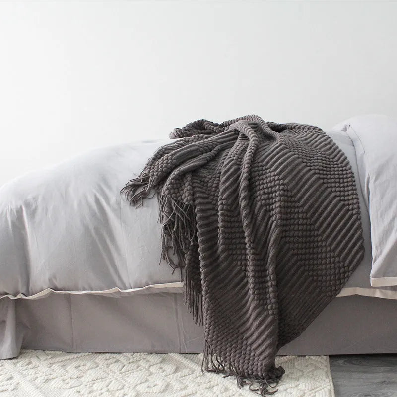 Small light grey polyester fleece blanket folded on a sofa