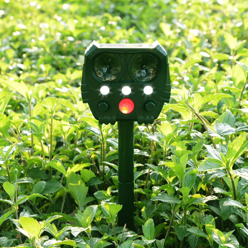 Green solar-powered ultrasonic animal repeller unit with LED light for outdoor pest control.