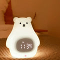 White silicone bear-shaped night light with remote control on a wooden bedside table.