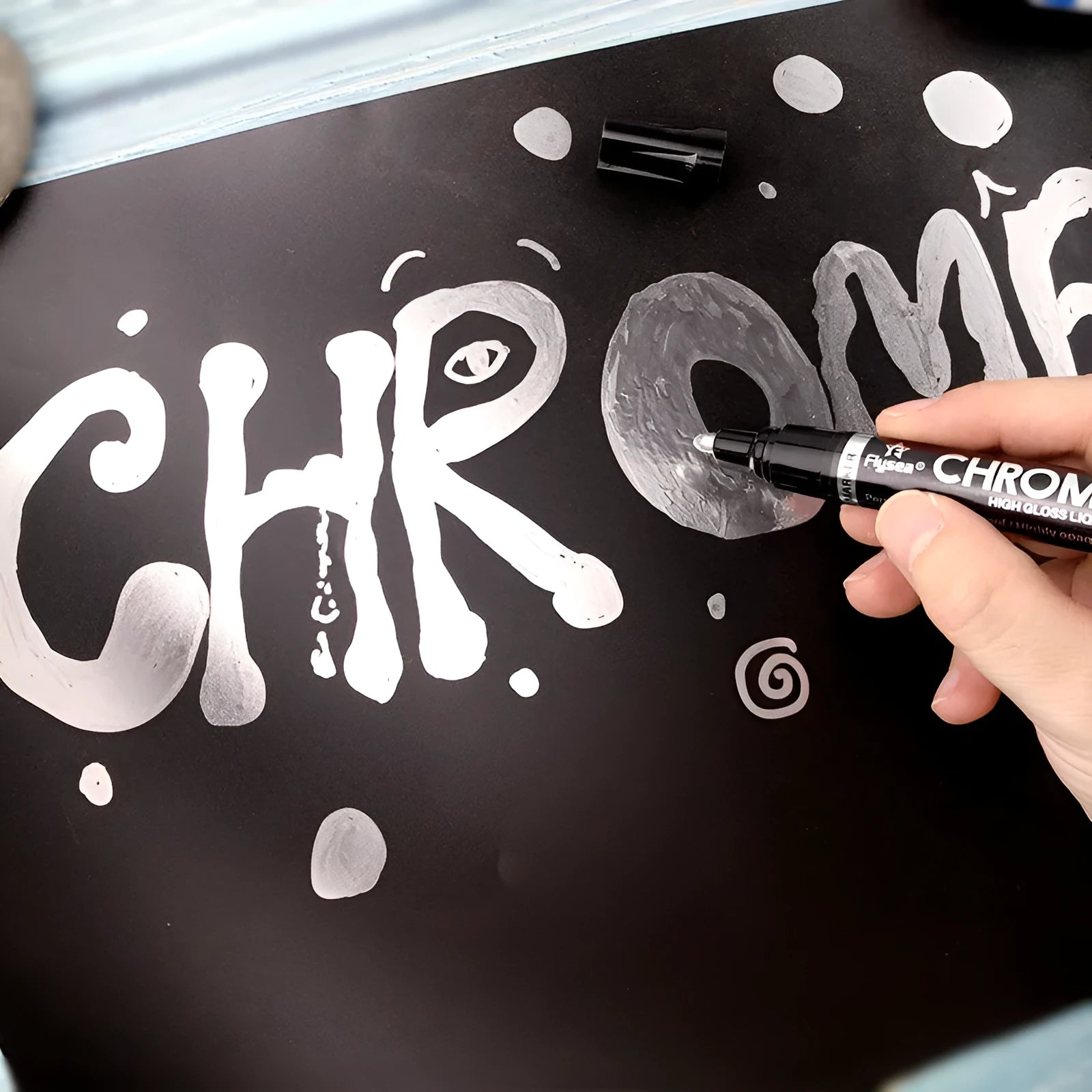 Chrome-plated reflective paint marker pen with 3.0mm tip on glass surface showing silver writing