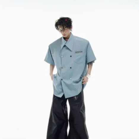 A man's loose-fitting short-sleeved casual shirt in a choice of black, blue, or white, showing lapel collar and metal decoration details.