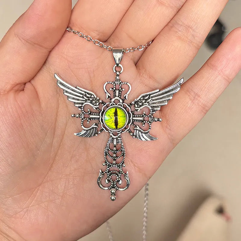 Close-up of a silver-coloured geometric pendant with wing details and a central cross on a chain.