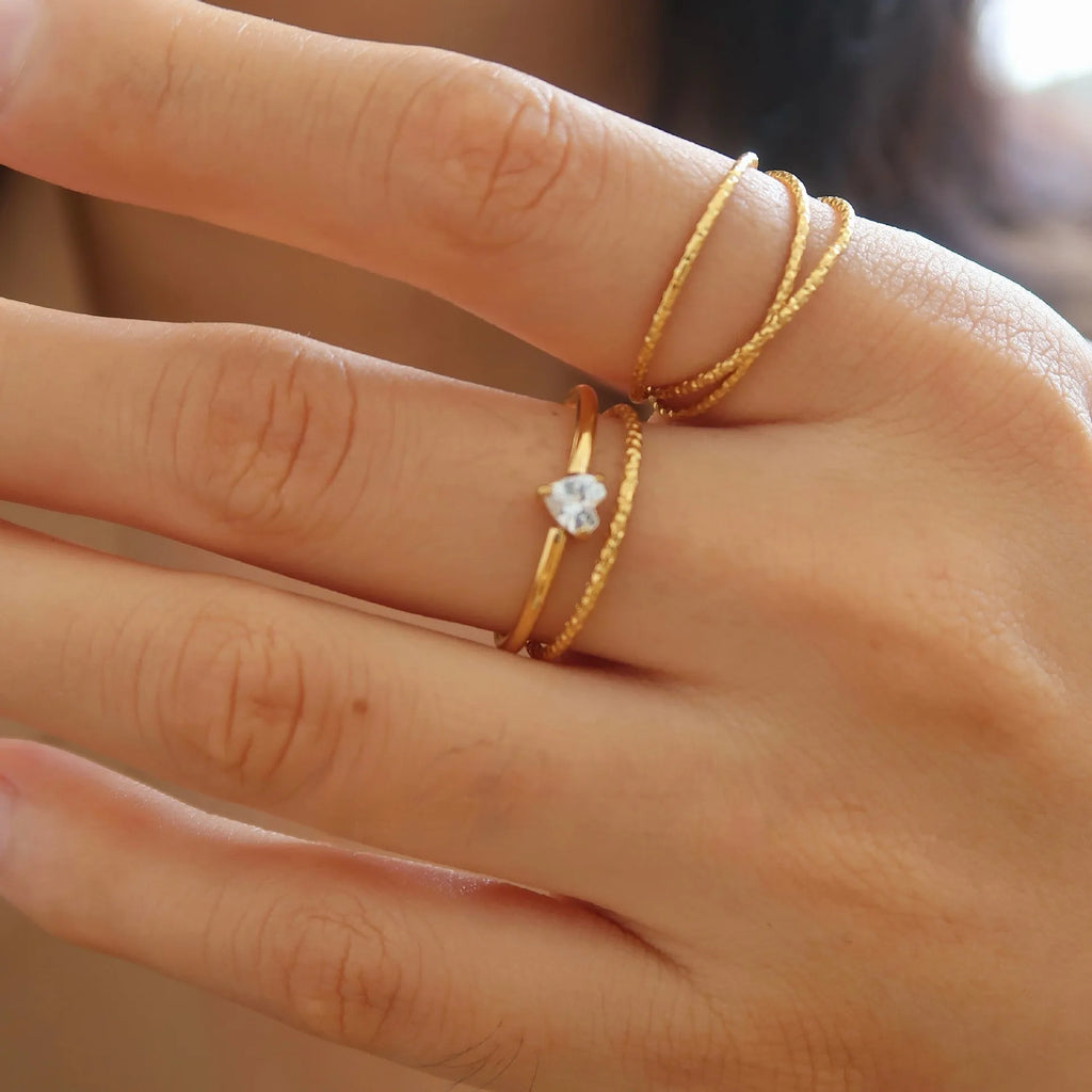 Golden heart-shaped stainless steel ring with electroplated finish shown in UK sizes 5-8